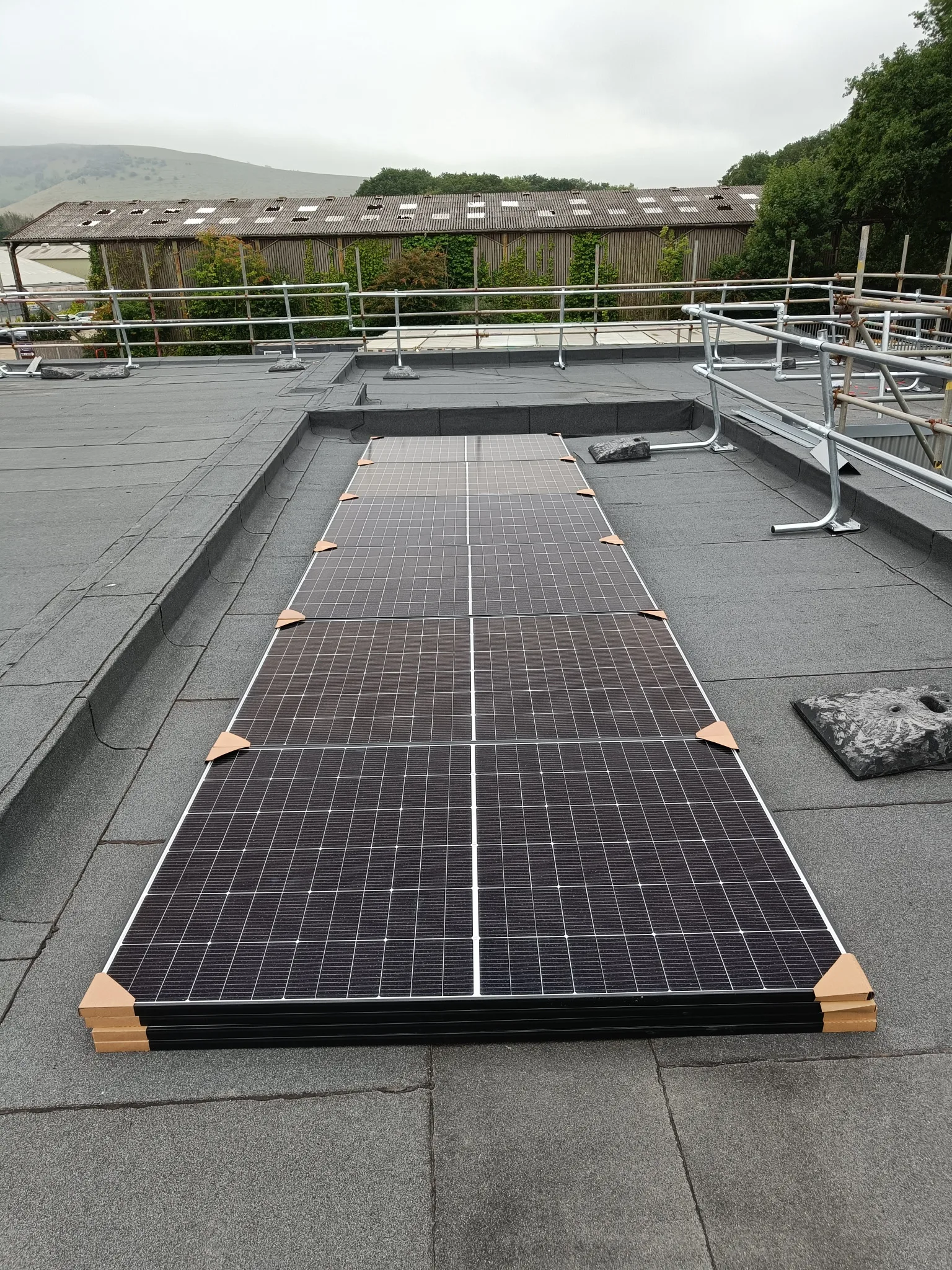 Solar panels positioned on a flat roof before installation in Small Dole